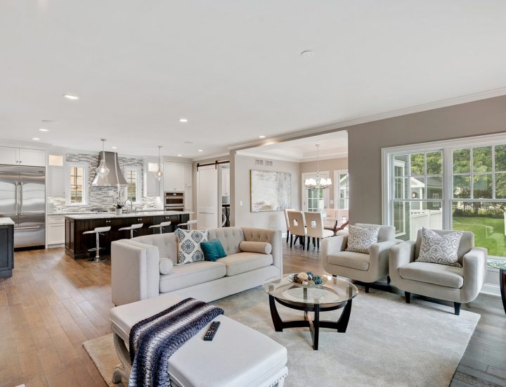 Modern living space with view of the kitchen, showcasing a cozy seating area, elegant decor, and a harmonious color palette that enhances the room's spacious feel.