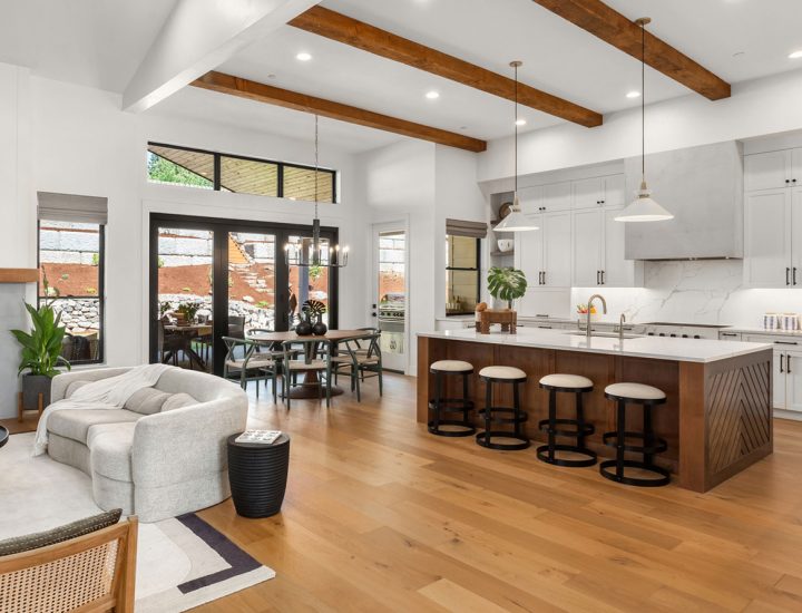 Expansive open plan living area featuring high ceilings with wooden beams, large windows, and a blend of rustic and modern decor elements.